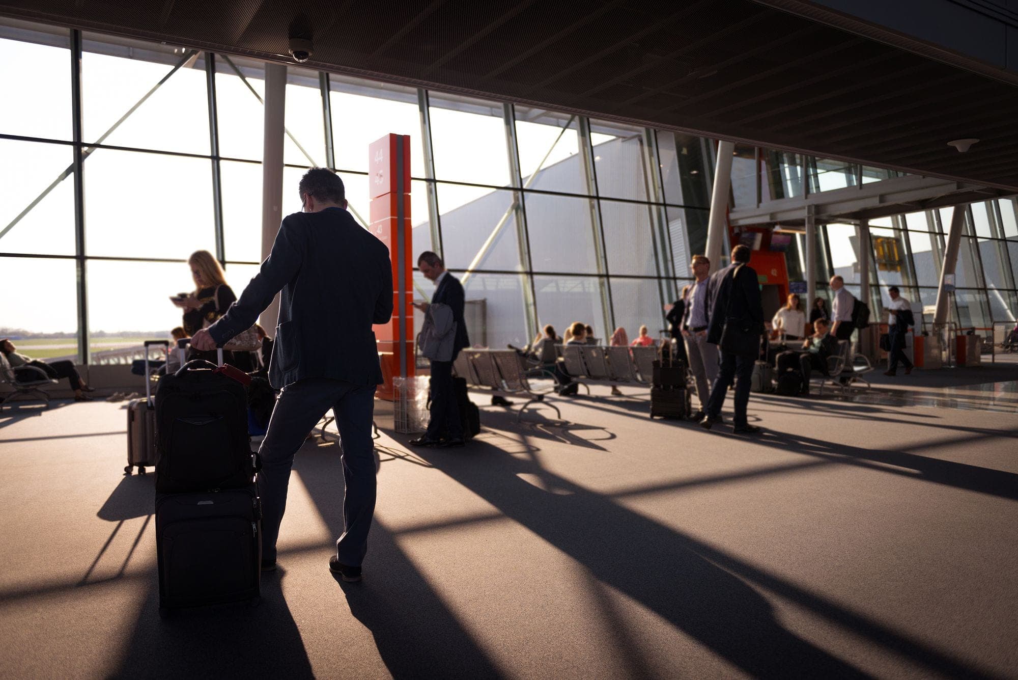 A traveller wheeling luggage through a bright airport terminal, the walk out a Riyadh arrival makes