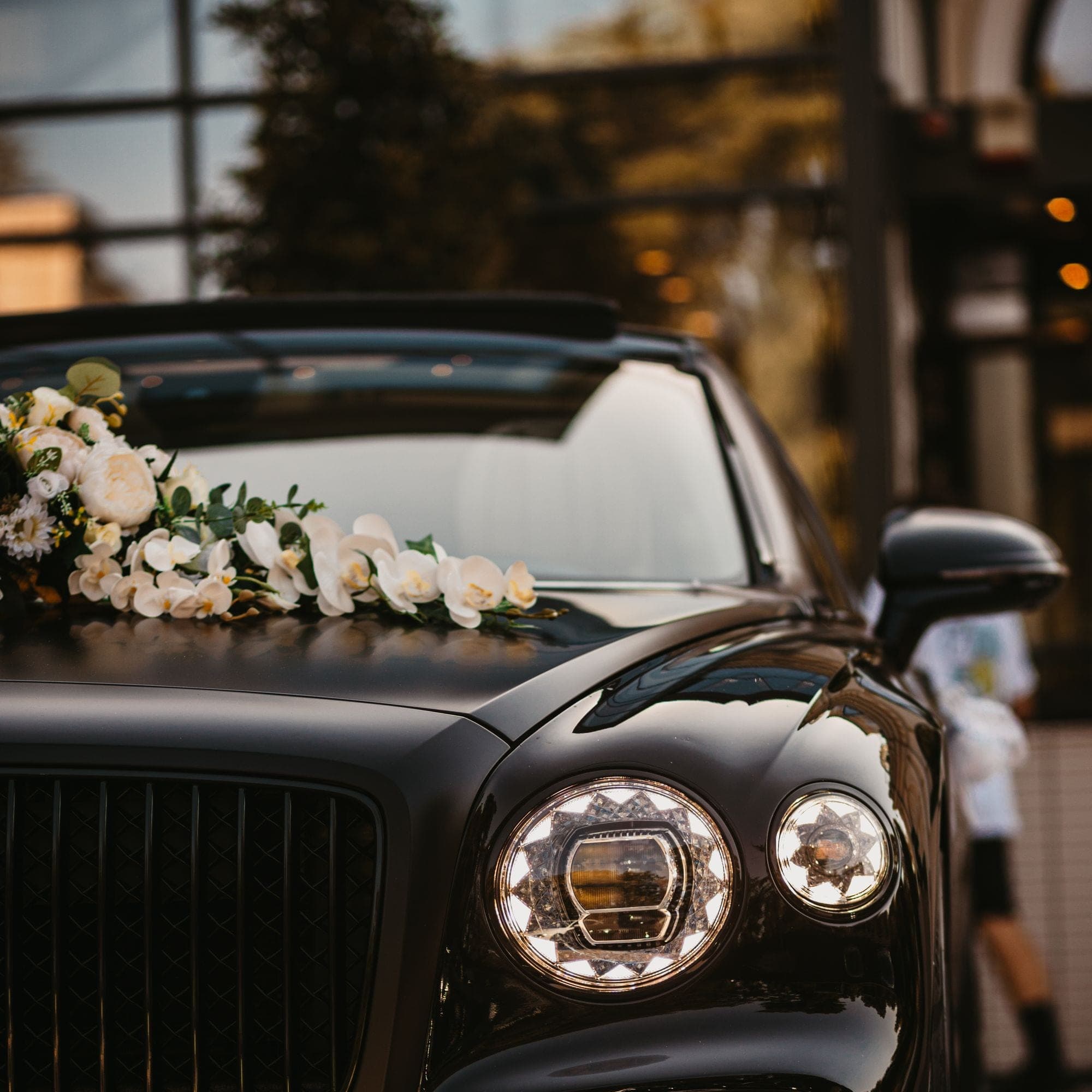 Black Bentley dressed with white flowers across the bonnet, the couple's car for the wedding