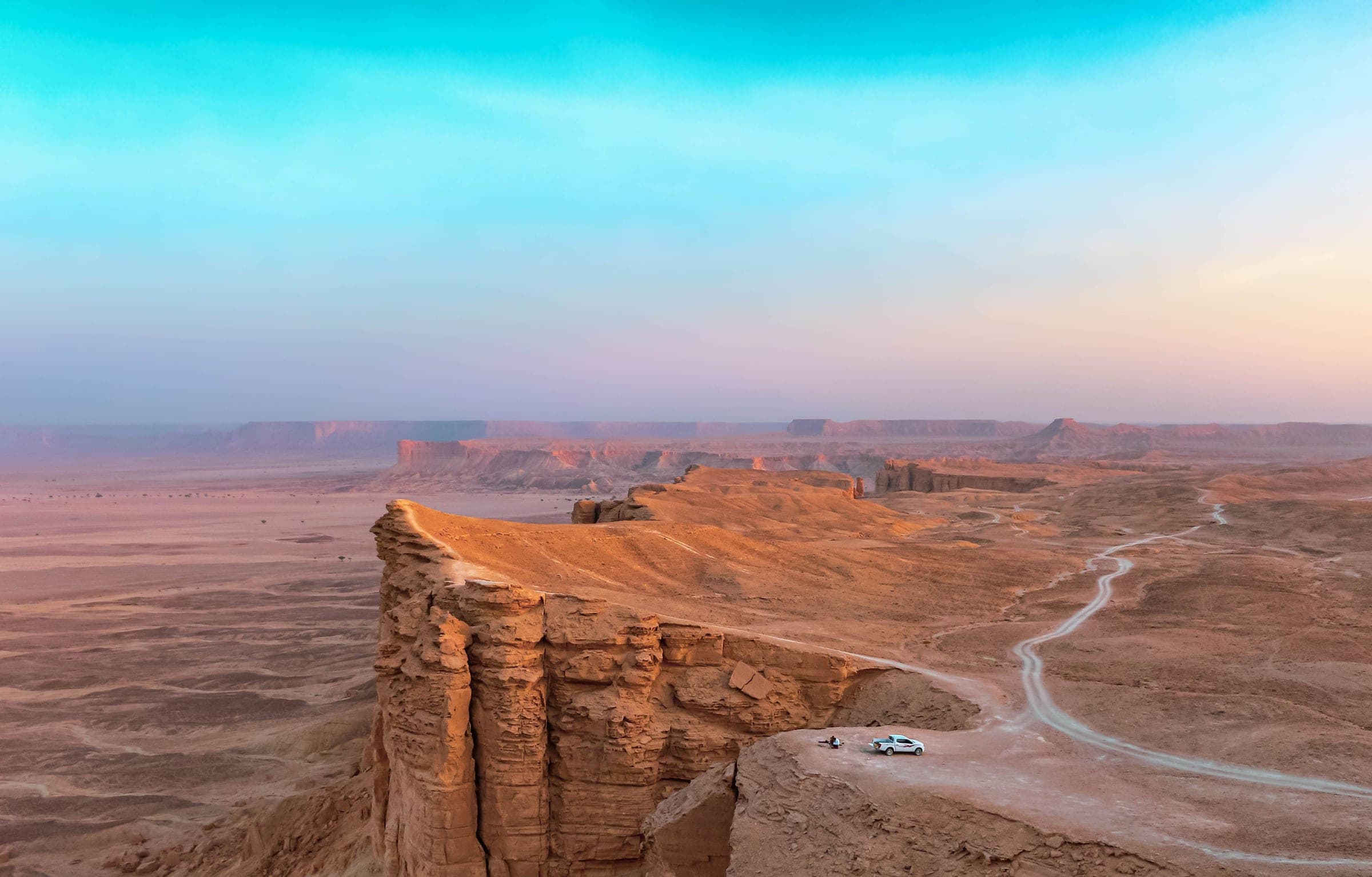 The Edge of the World cliffs on the Tuwaiq escarpment outside Riyadh, a car parked at the viewpoint above the ancient seabed