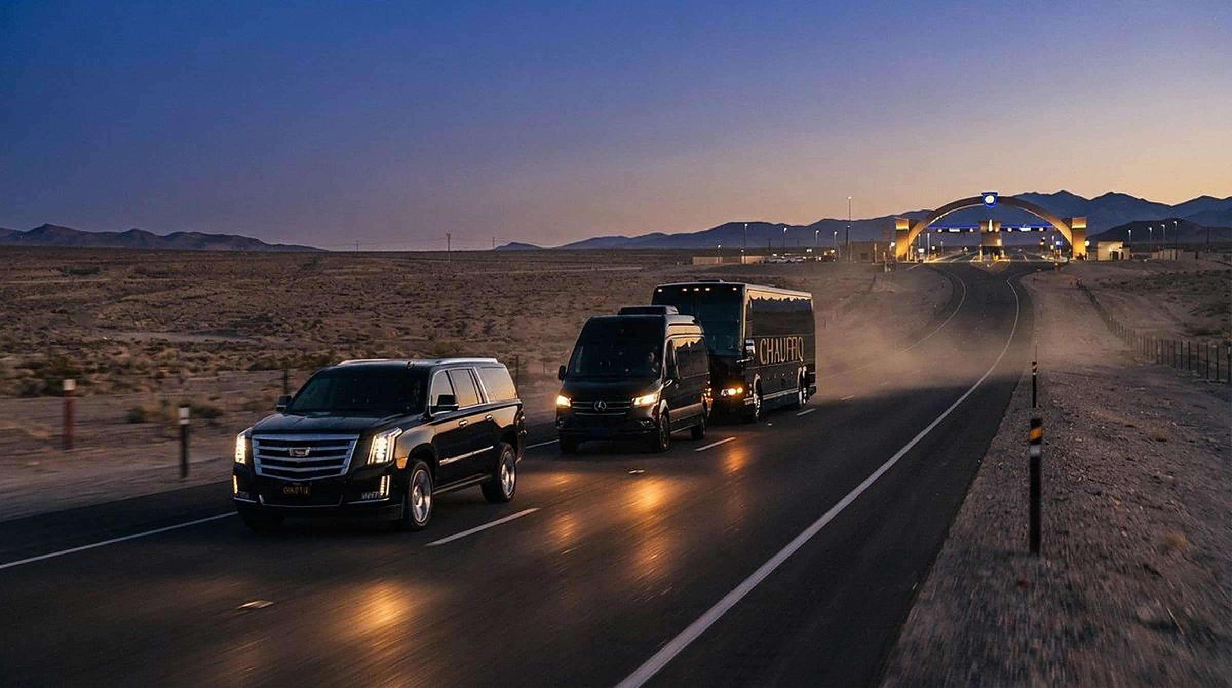 GCC cross-border chauffeur service, CHAUFFIQ convoy of an SUV, Sprinter and VVIP coach approaching a lit border crossing at dusk