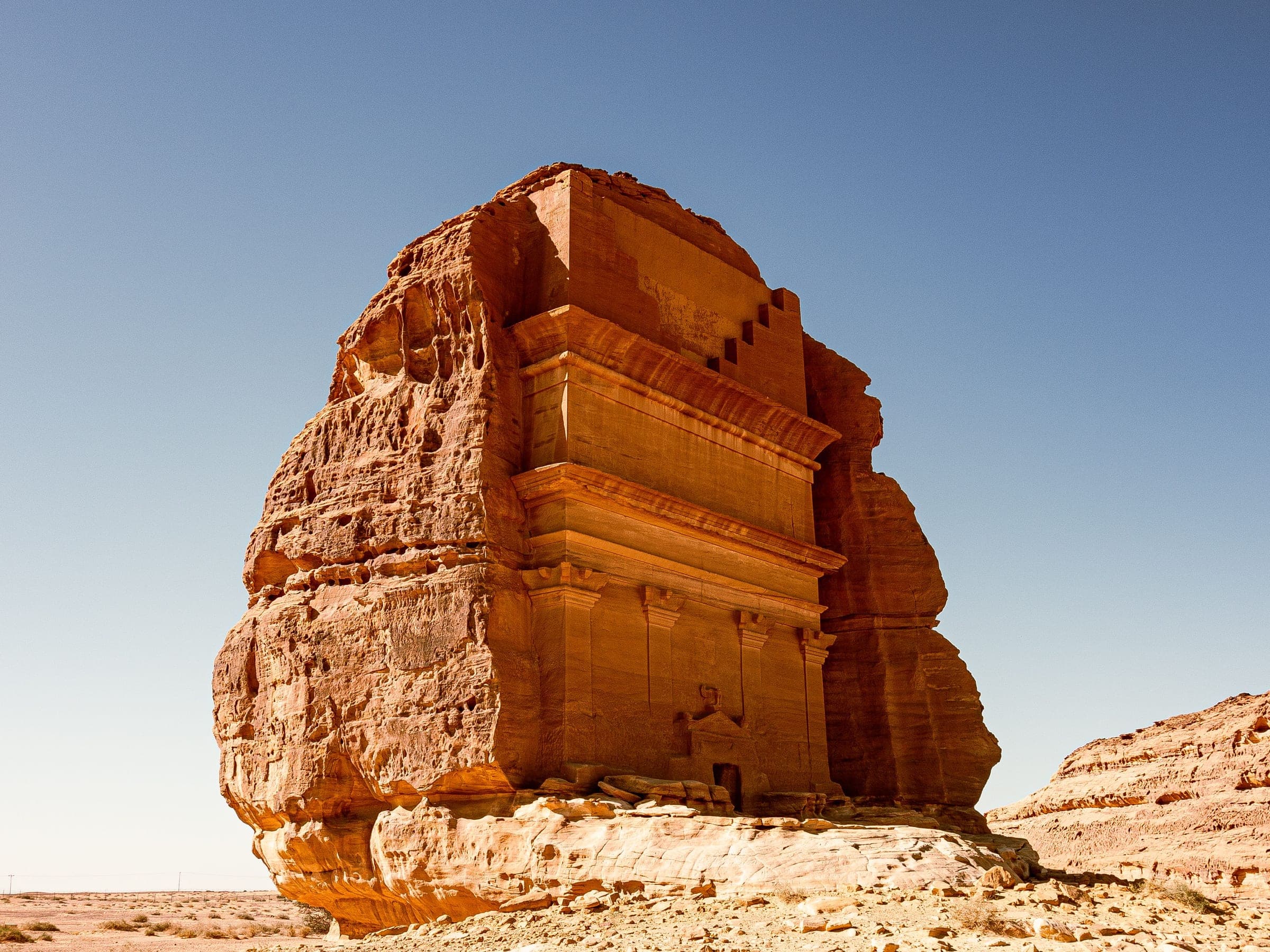 A rock-cut Nabataean tomb standing alone in the desert at Hegra, AlUla, the Kingdom's first UNESCO World Heritage site