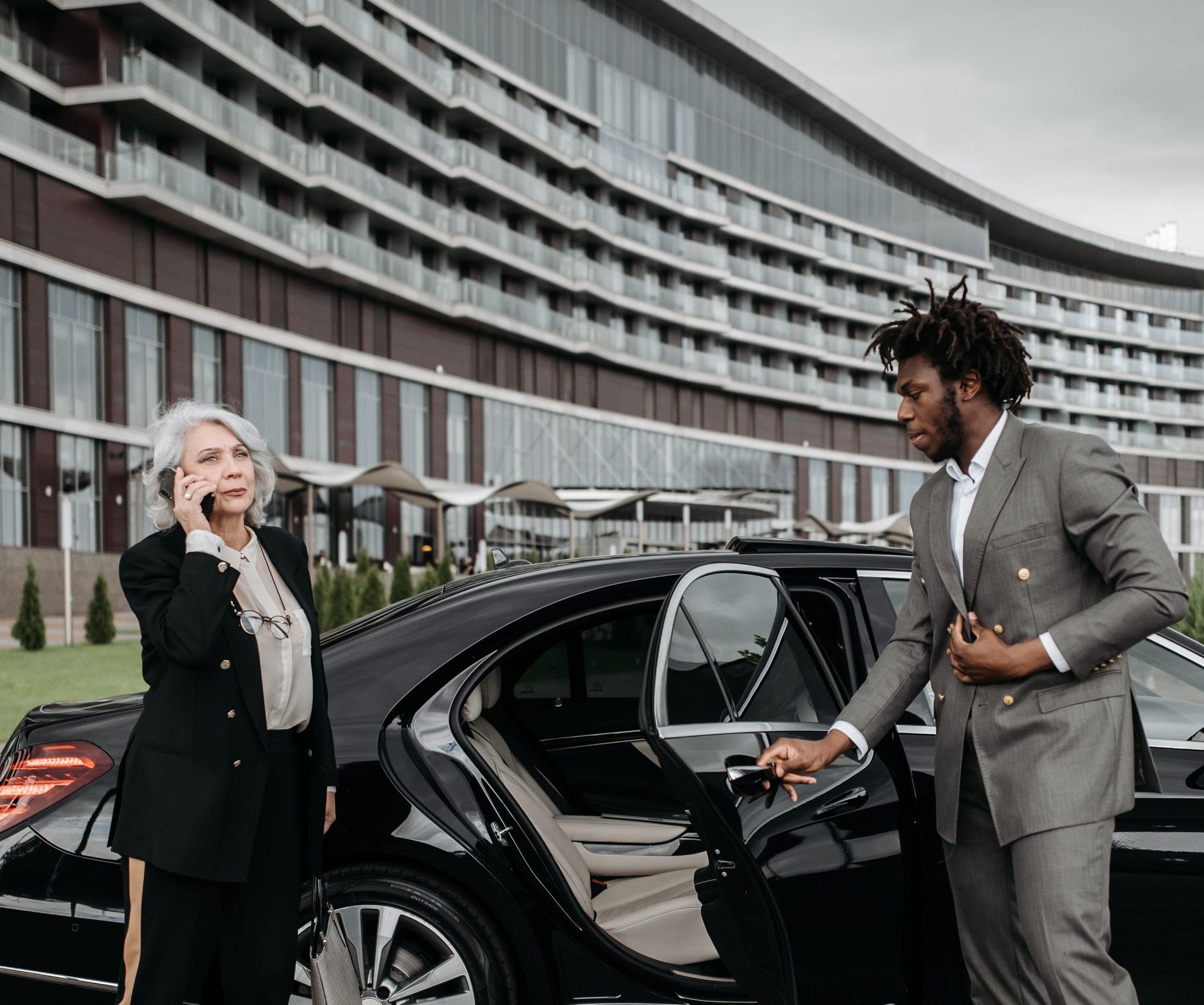 Chauffeur holding the rear door of a black Mercedes for a guest on a hotel forecourt