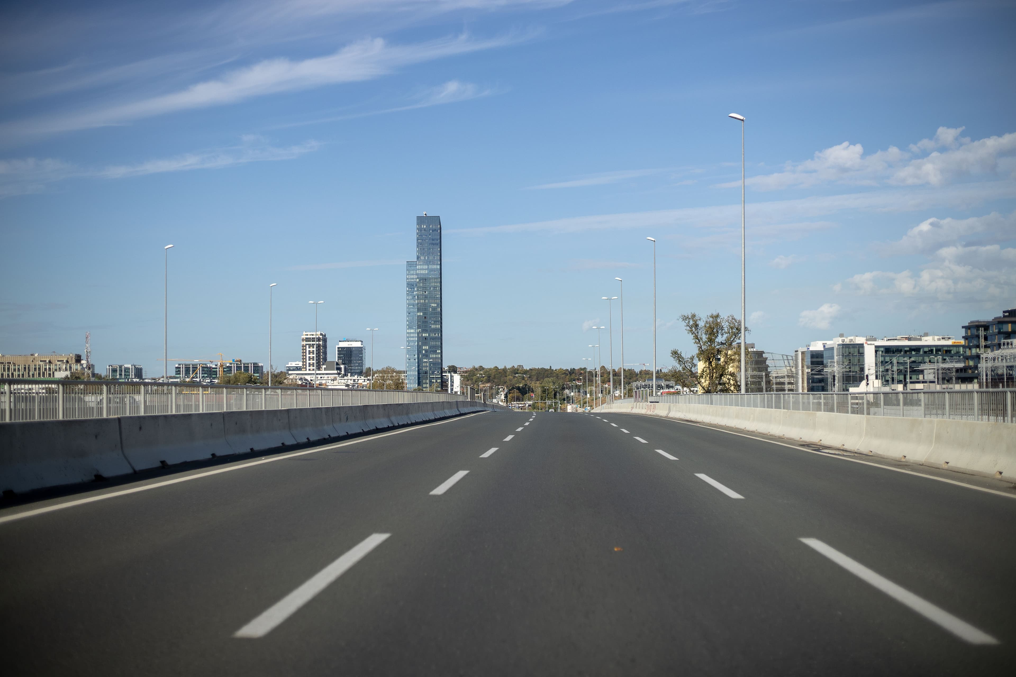 An open multi-lane highway running toward a city skyline, the road a departure is timed against