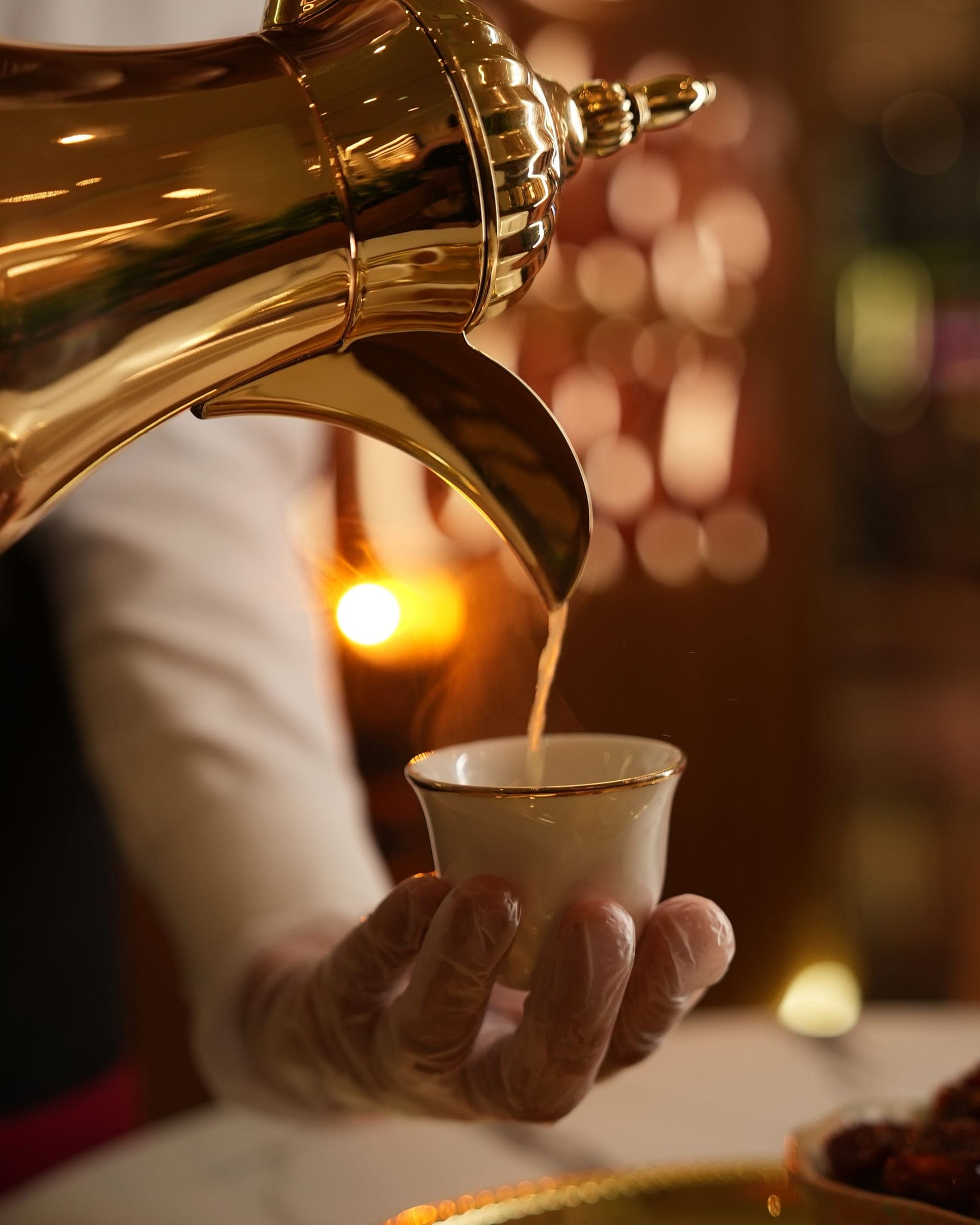 VIP concierge chauffeur service Riyadh, Arabic coffee poured from a gold dallah into a finjan, dates on the tray
