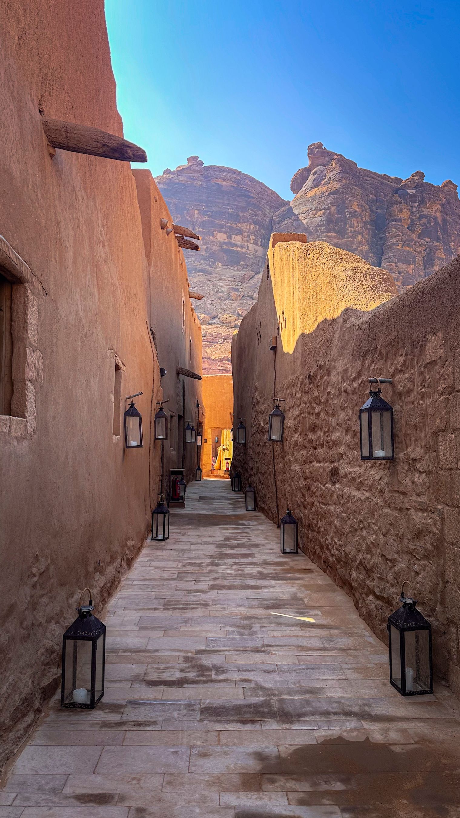 AlUla Old Town at golden hour, the mud-brick quarter below the sandstone cliffs
