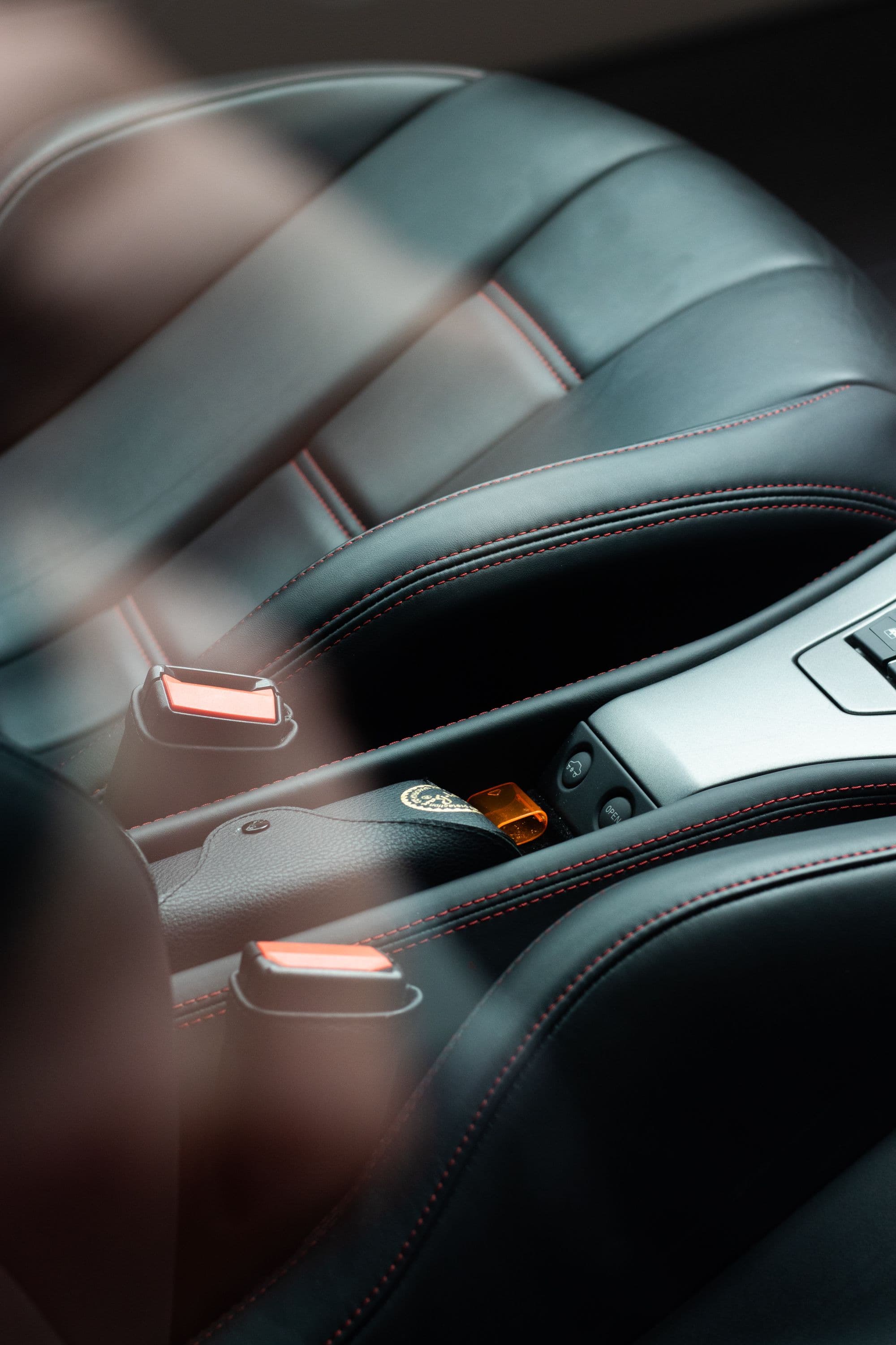 Black leather trim detail with contrast stitching under ambient light
