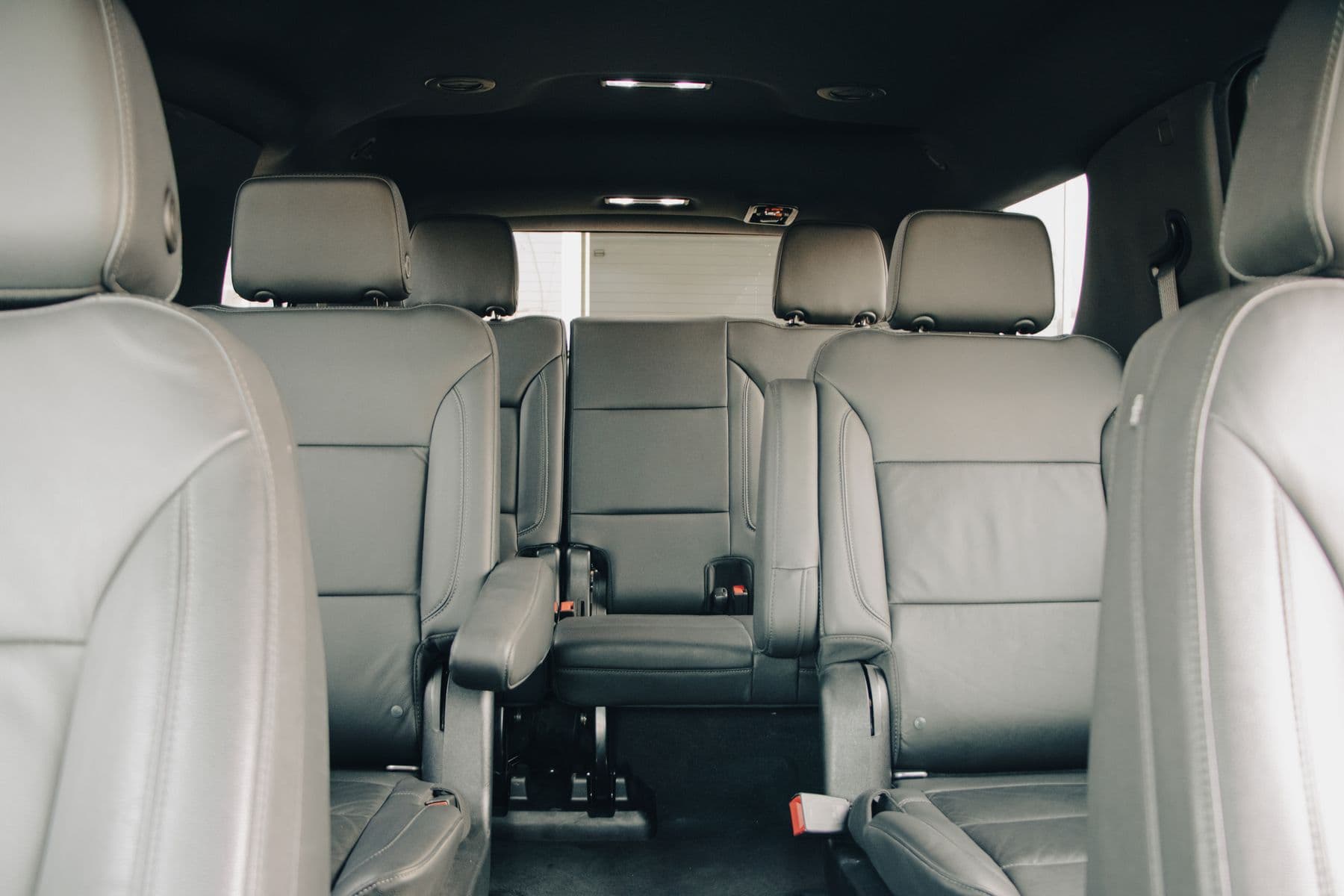 Three rows of leather seats in a full-size SUV cabin, centre aisle to the rear bench