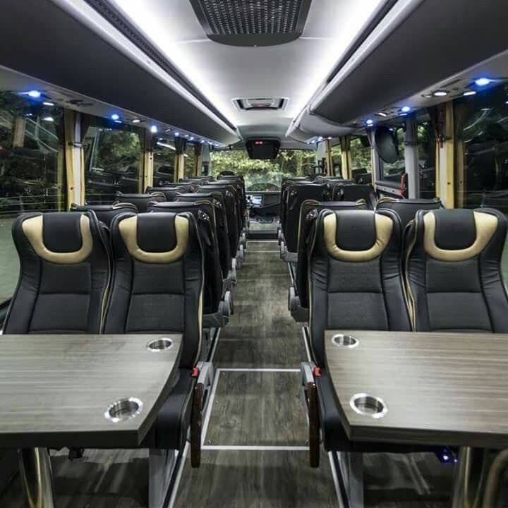 Luxury coach seats in black quilted leather with folding wood tables