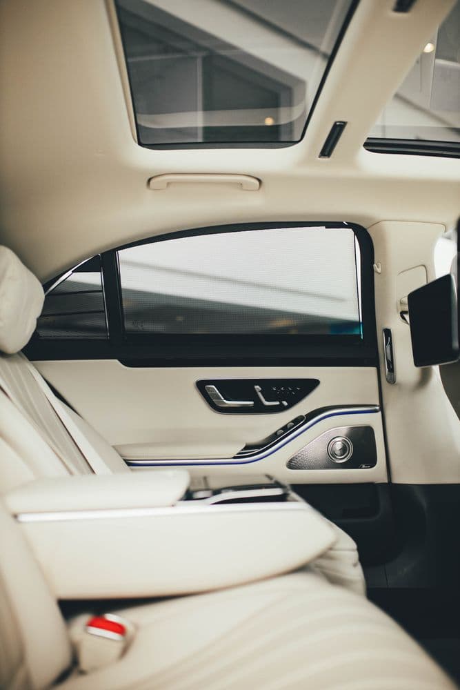 Cream leather rear cabin of a Mercedes-Benz S-Class with window shades drawn