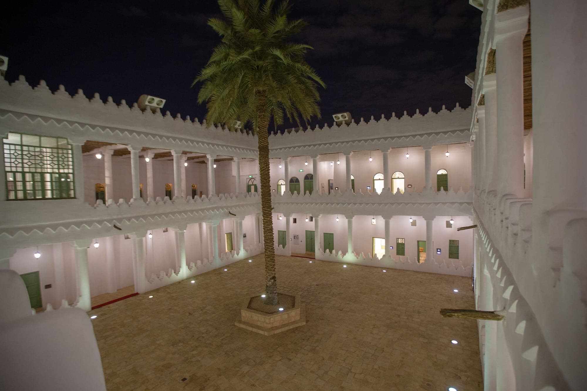 The lit courtyard of Murabba Palace at night, a palm at its centre, in the King Abdulaziz Historical Centre beside the National Museum