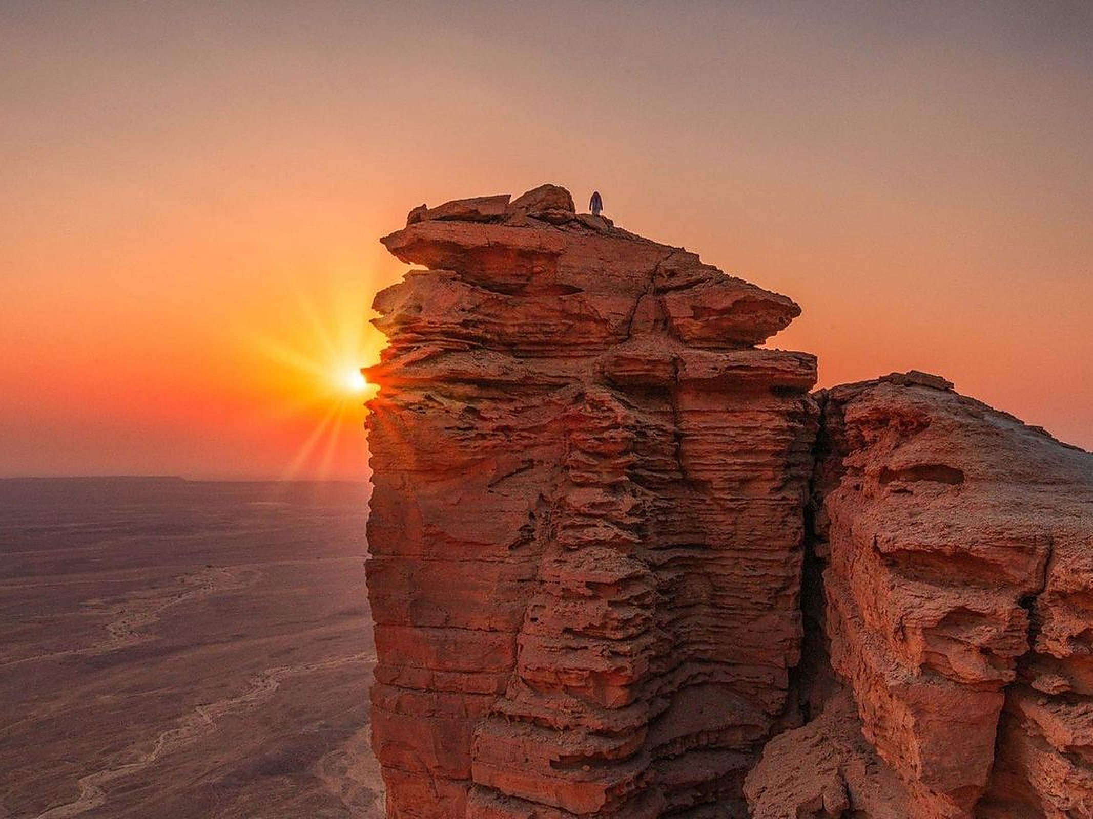 Riyadh sightseeing tour, a lone figure on the Edge of the World cliffs at sunset outside Riyadh